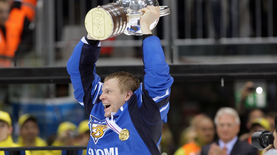 A Finnish ice hockey player holding a trophy and smiling